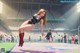 A woman in a black bodysuit and red boots standing on a wrestling ring.