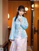 A woman in a blue and pink hanbok standing in a hallway.