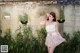 A woman standing in front of a wall of plants.