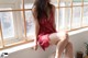 A woman in a red lingerie sitting on a window sill.