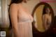 A woman in a white lingerie looking at herself in the mirror.