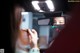 A woman applying lipstick in front of a rear view mirror.