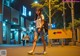 A woman walking down the street at night with a backpack.