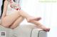 A woman sitting on top of a couch with her legs crossed.