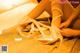 A woman tying up her wedding shoes on a bed.