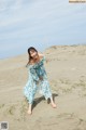 A woman in a blue dress is walking on the beach.