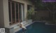 A woman in a white bikini sitting on the edge of a swimming pool.